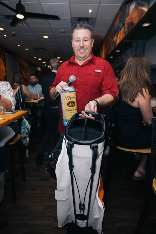 Man with golf bag and microphone in his hand