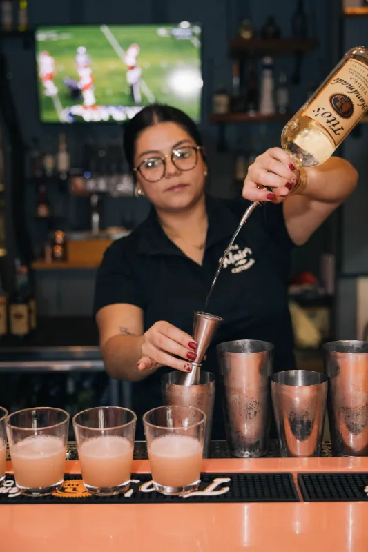 Lady pouring a drink behind the bar counter