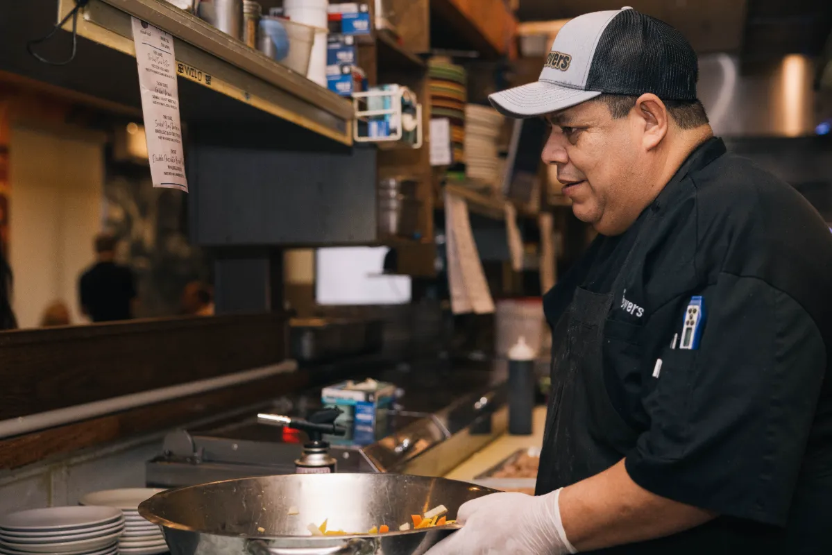 Chef preparing a meal in the kitchen at Leftover Restaurant